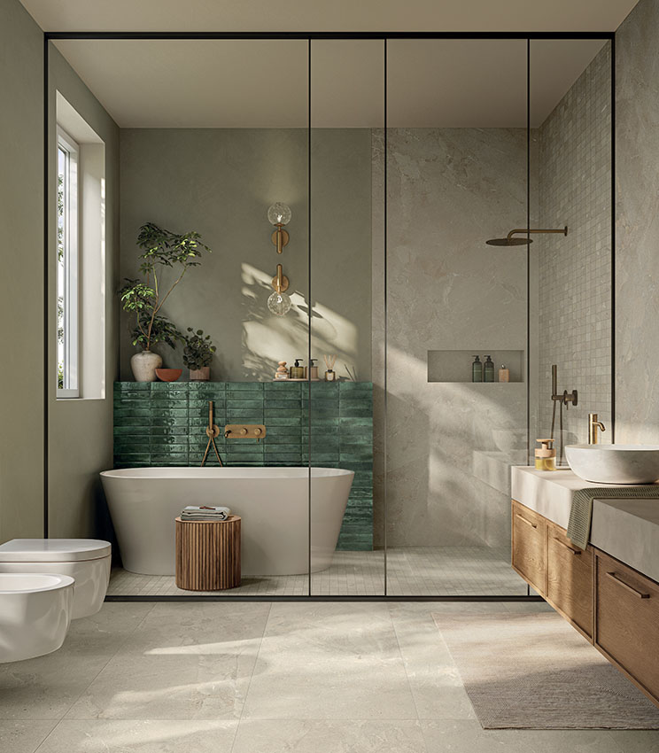 Modernes Badezimmer mit Oberflächen aus den Kollektionen Revel Dune, Mosaico Dune und Workshop Jade, mit freistehender Badewanne, glänzender grüner Wand, großzügiger Glasdusche, Waschtischunterschrank aus Holz und natürlichem Licht auf den neutralen Oberflächen.