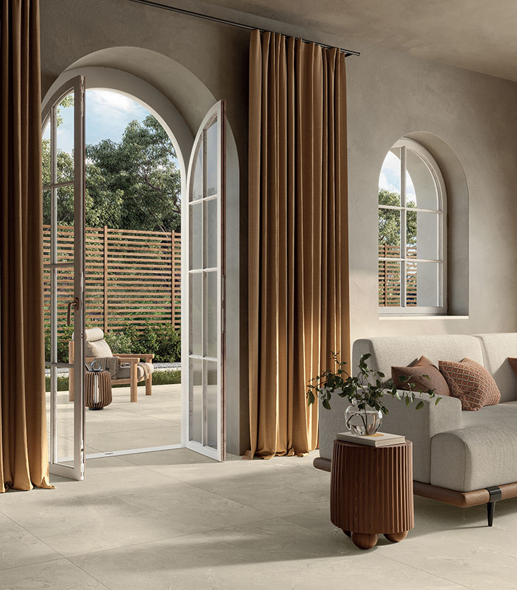 Modernes Wohnzimmer mit Feinsteinzeugboden in Steinoptik, natürlichen Farbtönen und großen Öffnungen nach außen für ein elegantes, lichtdurchflutetes Ambiente.