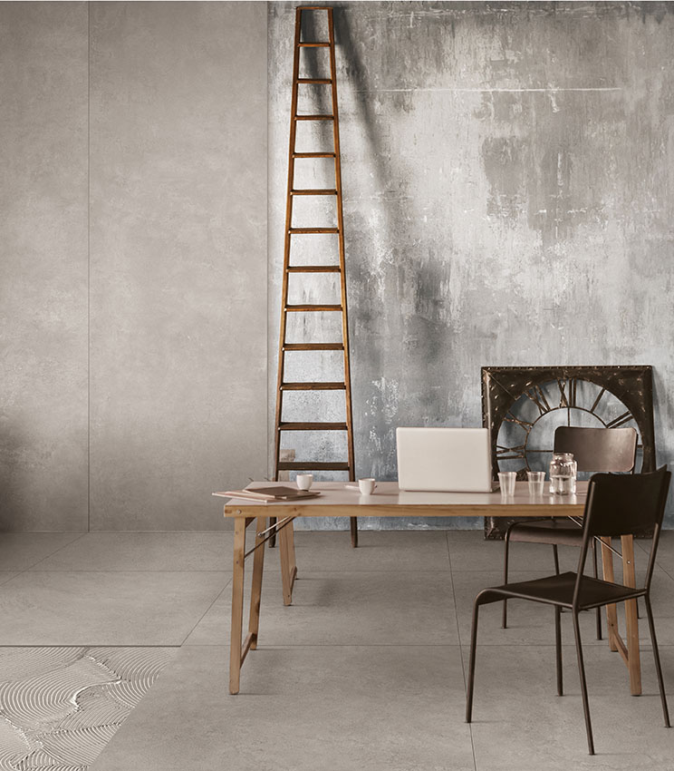 Büro im Industrial Style mit Boden in Zementoptik, strukturierten Wänden, Holztreppe und minimalistischen Möbeln aus Holz und Metall.