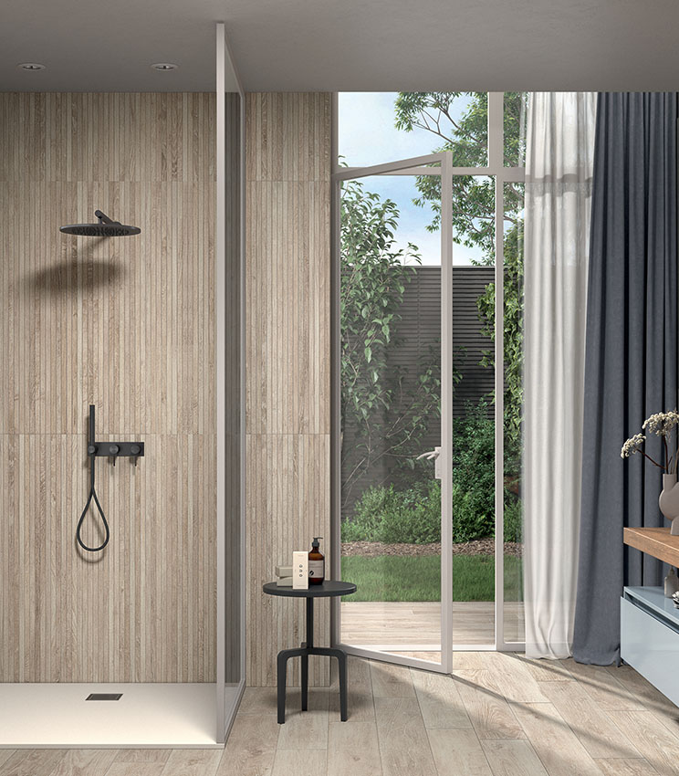 Moderna stanza da bagno dalle tinte chiare e naturali, con pavimento e doccia in gres porcellanato effetto legno, e con un rivestimento strutturato che esalta le qualità materiche della ceramica pigmentata.