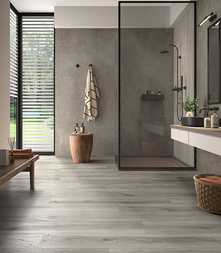 Moderna stanza da bagno pavimentata con doghe di gres porcellanato effetto legno grigio e rivestimento con gres effetto pietra grigio. Collezione Borealis di Panaria Ceramica.