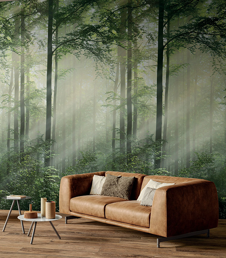 Wohnbereich mit Ledersofa und eindrucksvoller Keramikwandverkleidung aus dünnen Platten im Wallpaper-Look, die mit fotografischem Realismus einen Wald darstellt