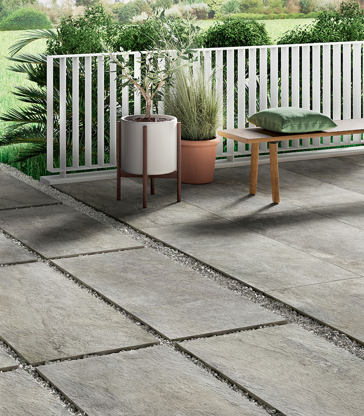 Blick auf einen Außenbodenbelag aus Feinsteinzeug in Steinoptik, 20 mm stark, teils Terrasse (mit Klebstoff verlegt) und teils Gehweg mit Trockenverlegung auf Kies | Pierre de Rêves Kollektion von Panaria Ceramica
