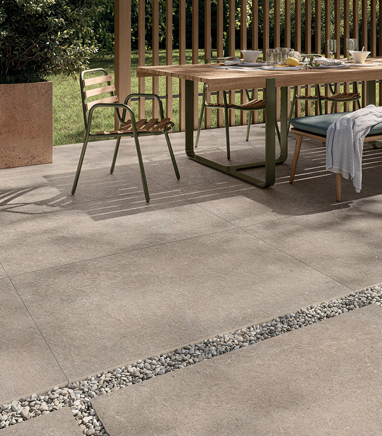 Blick auf einen Frühstückspatio mit 20 mm starkem Außenfeinsteinzeug in Steinoptik in Sandfarbe, teils mit Klebstoff und teils trocken auf Kies verlegt | Surround Kollektion von Panaria Ceramica