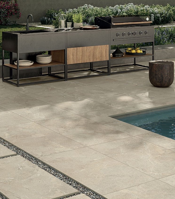 Poolbereich mit Feinsteinzeugboden in Steinoptik, Outdoor-Küche und modernen Möbeln für ein elegantes, widerstandsfähiges und funktionales Ambiente.