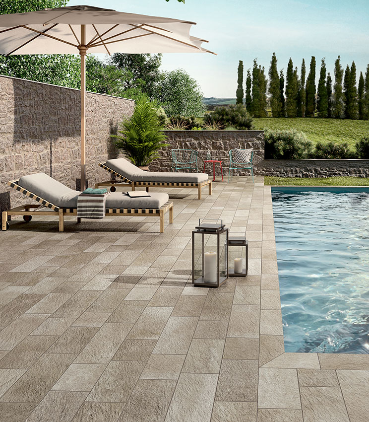 Poolbereich mit Feinsteinzeugboden in Steinoptik, Sonnenliegen und Outdoor-Möbeln für ein elegantes, natürlich wirkendes und widerstandsfähiges Ambiente.