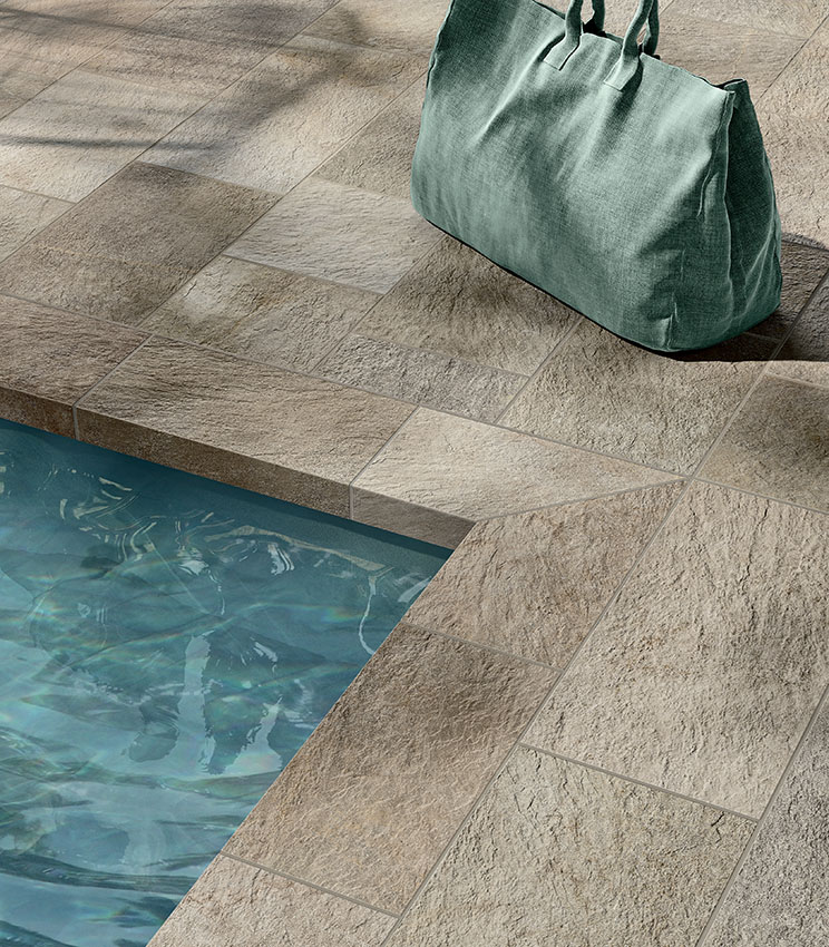 Detail eines Poolrands mit Feinsteinzeug in Steinoptik, strukturierter Oberfläche und natürlichen Farbtönen für ein elegantes und widerstandsfähiges Ergebnis.